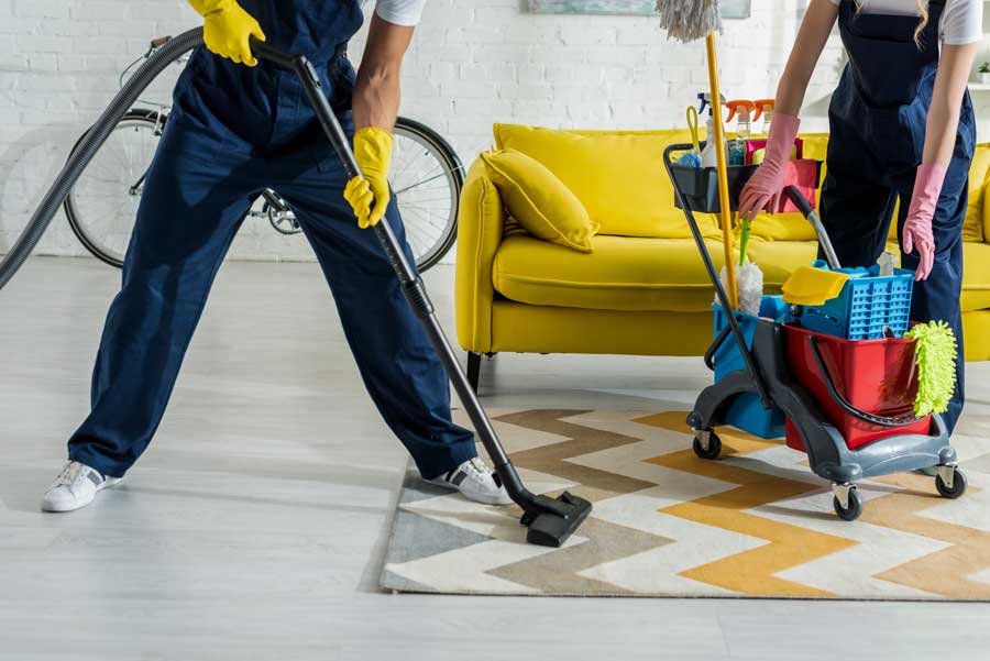 cropped-view-of-cleaners-in-overalls-cleaning-apar-XXJP3SX